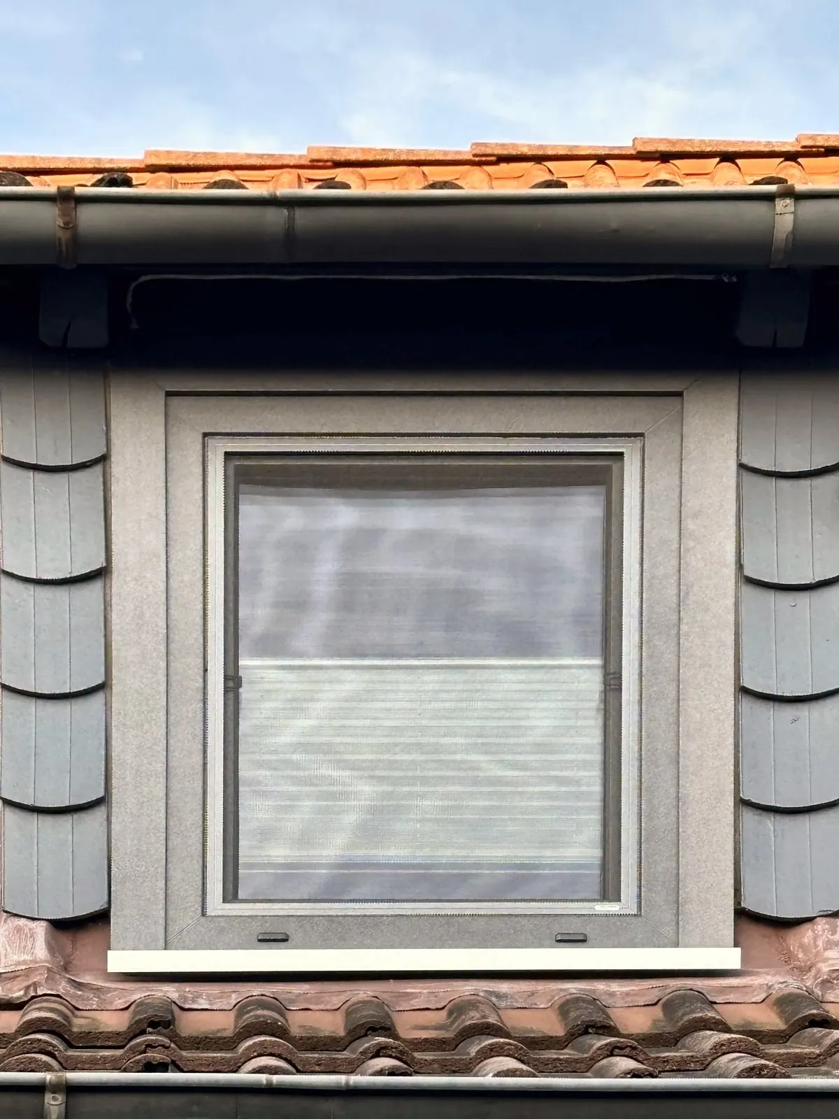 Gaubenfenster mit anthrazitfarbener Verkleidung in einem Ziegeldach