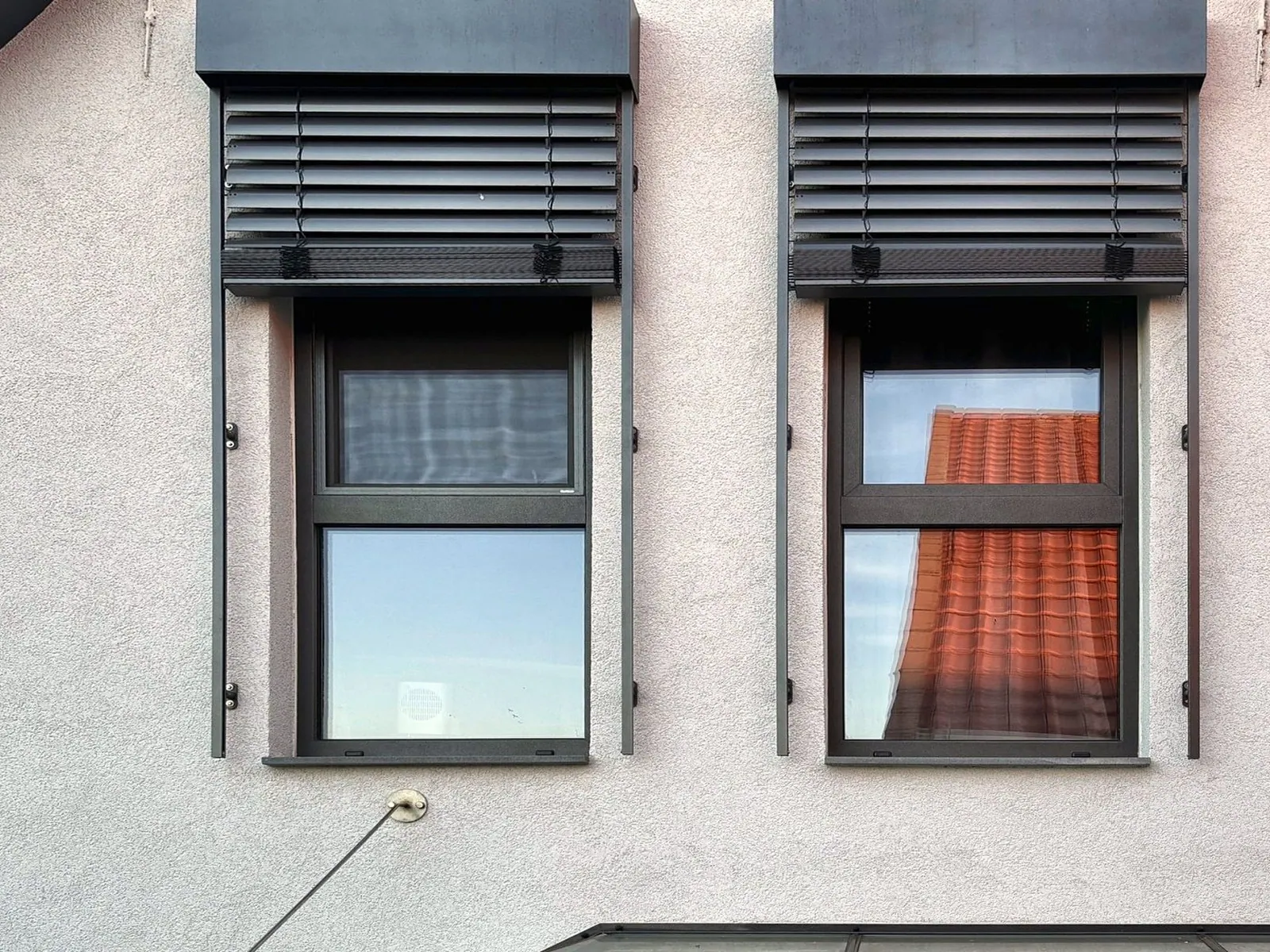 Zwei Giebelfenster mit halb heruntergefahrenen Raffstores in Anthrazit